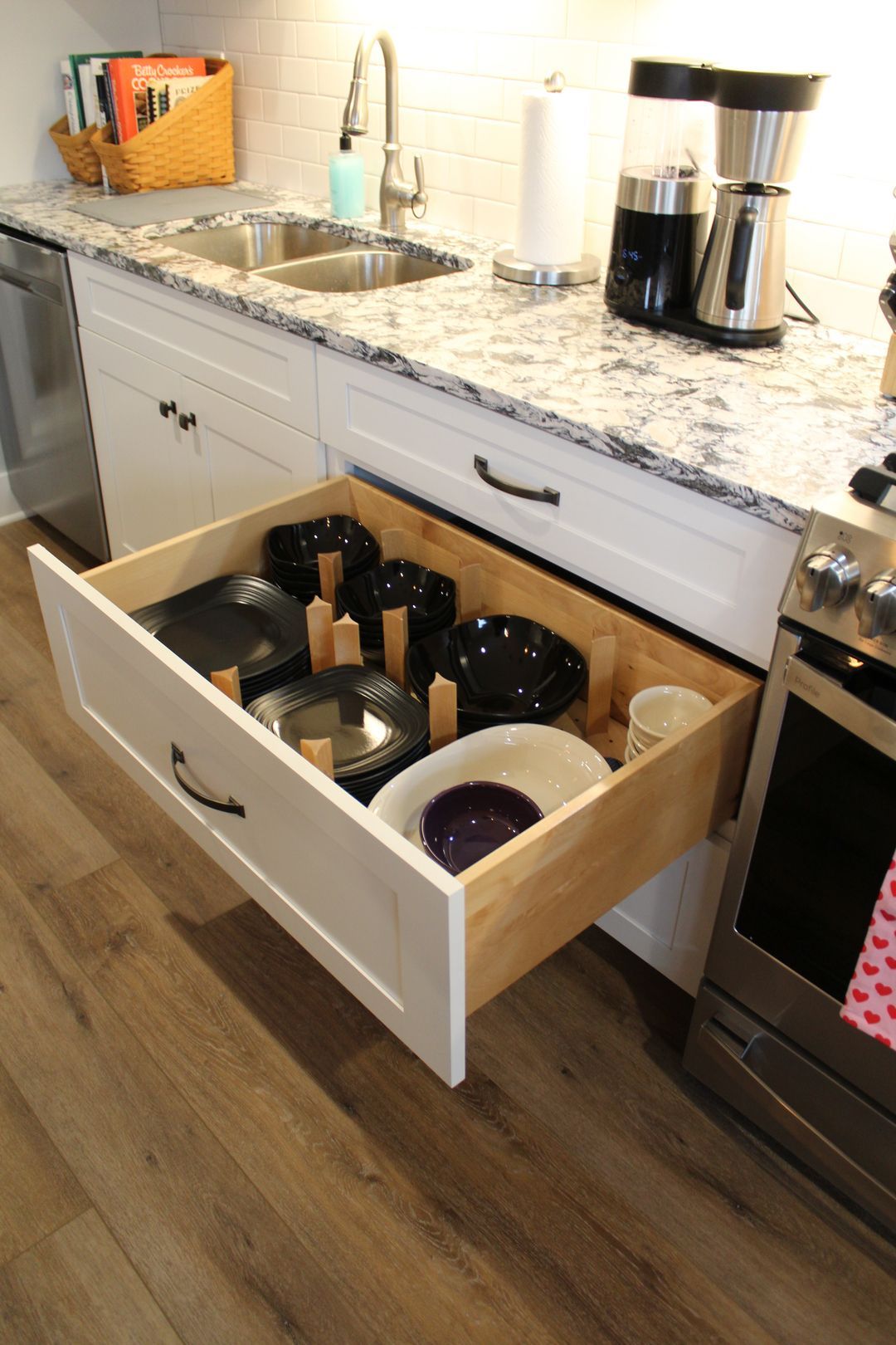 Kitchen drawer filled with pots, pans, and dishes beneath a granite countertop
