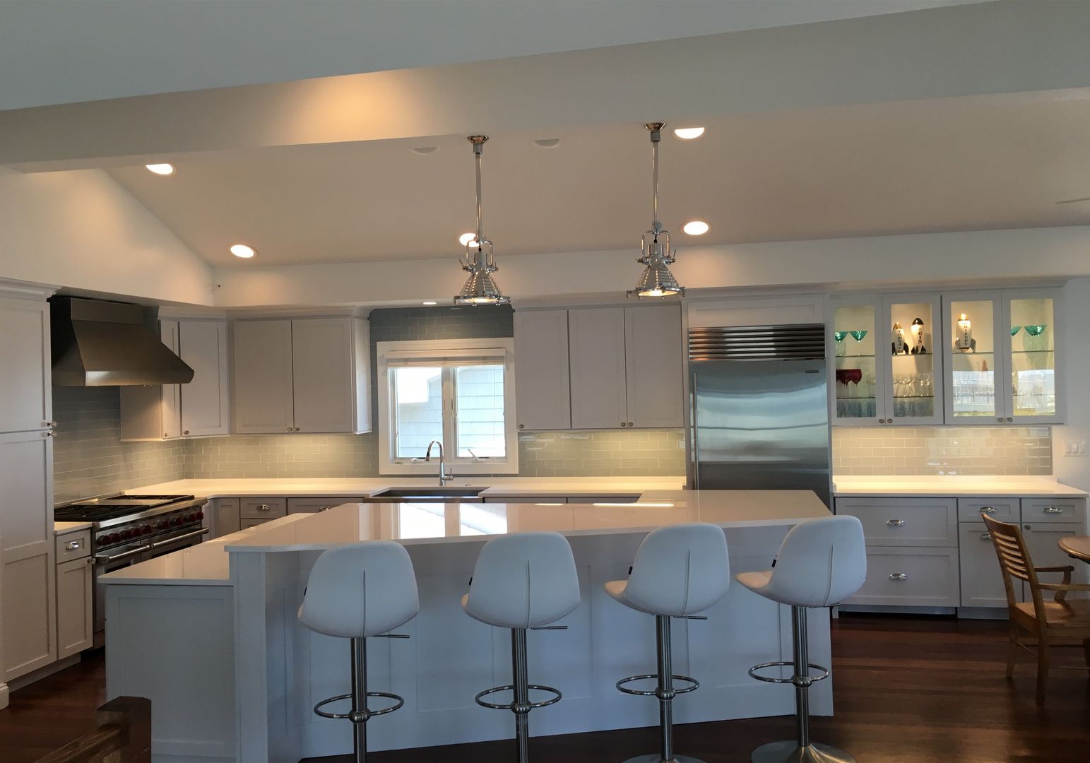 Bright modern kitchen with gray cabinets, white island, bar stools, and stainless steel appliances