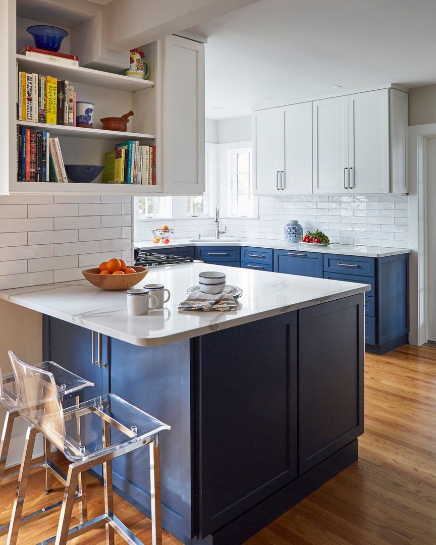 Bright modern kitchen with dark island, white cabinets, tiled backsplash, and bar stools