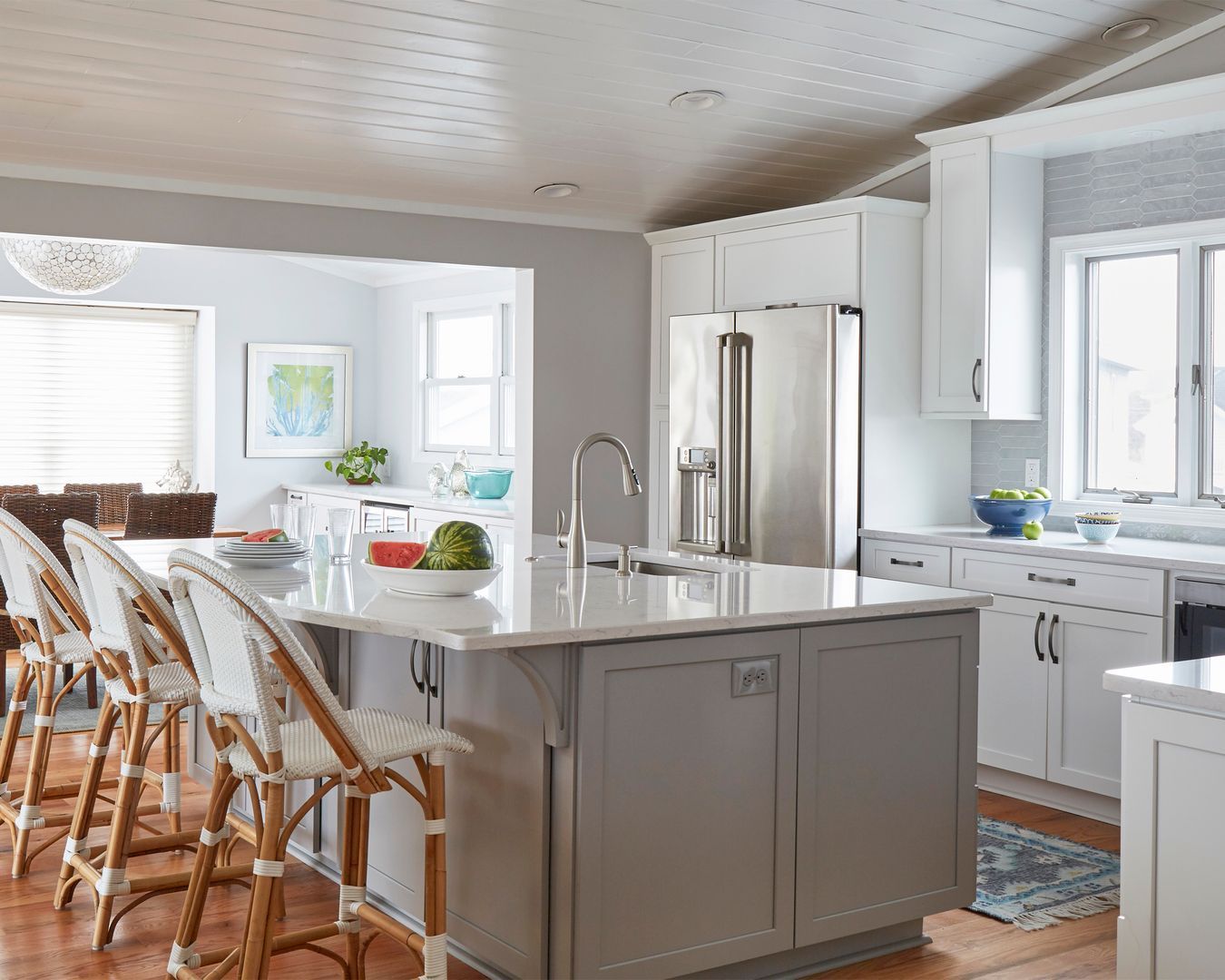 Bright modern kitchen with white cabinets, stainless fridge, and a large island with barstools