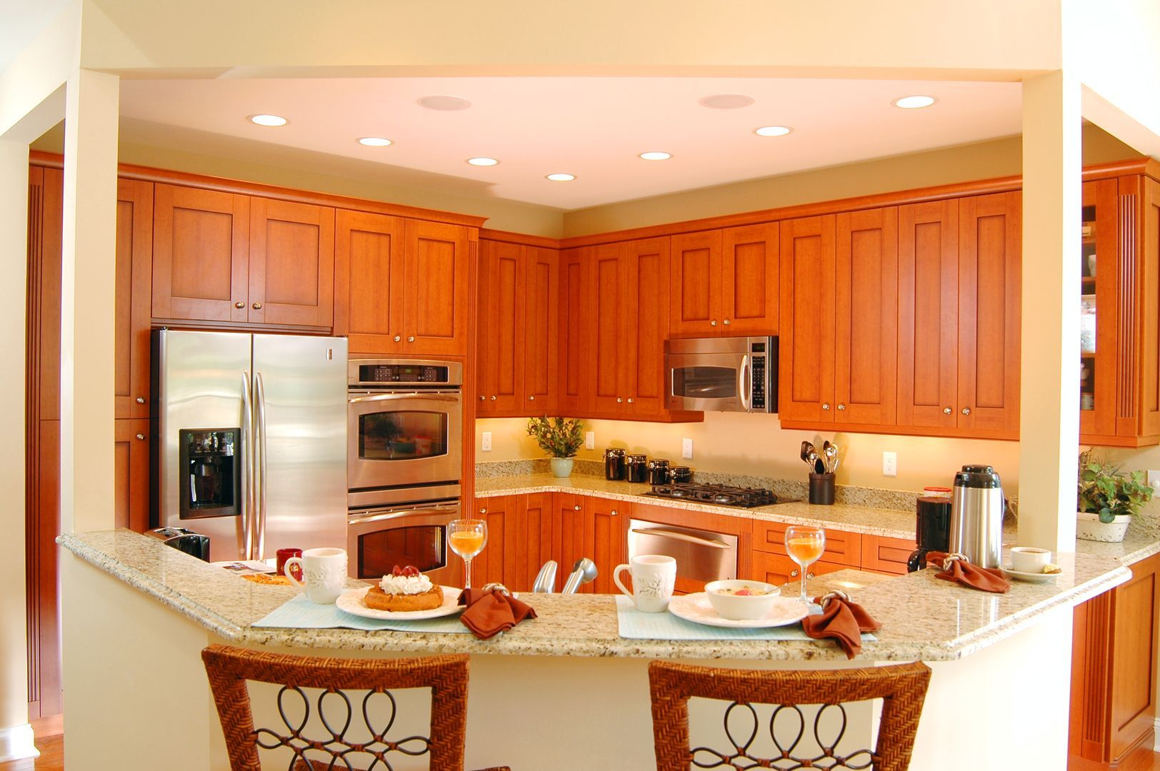 Bright kitchen with wooden cabinets, stainless steel appliances, and a granite island with barstools