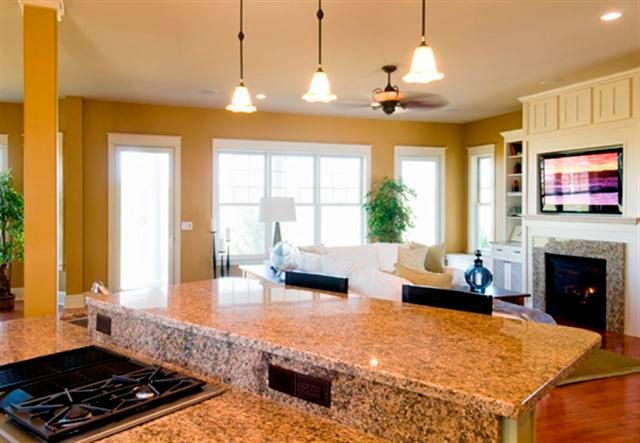 Modern kitchen and living room with granite island, white sofas, fireplace, and large windows
