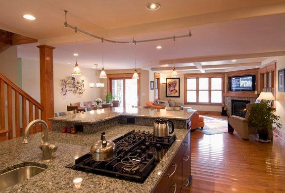 Spacious modern kitchen and living area with granite island, wood floors, and warm lighting