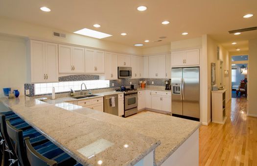 Bright modern kitchen with white cabinets, granite island, stainless appliances, and hardwood floors