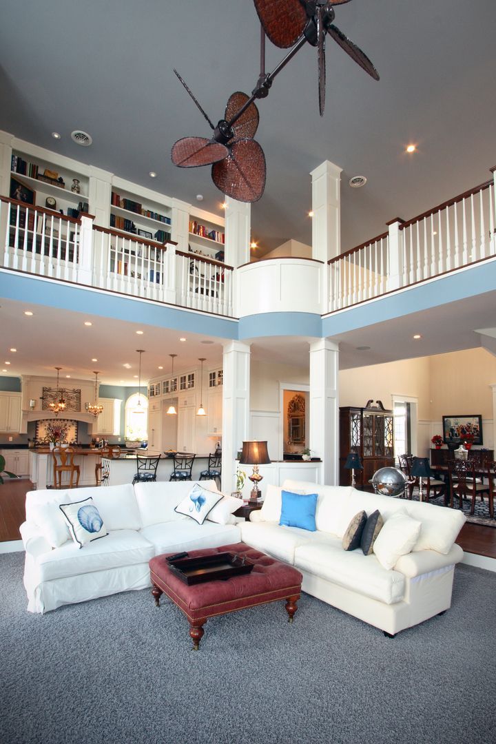 Bright open living room with white sectional sofa, red coffee table, balcony, and ceiling fans