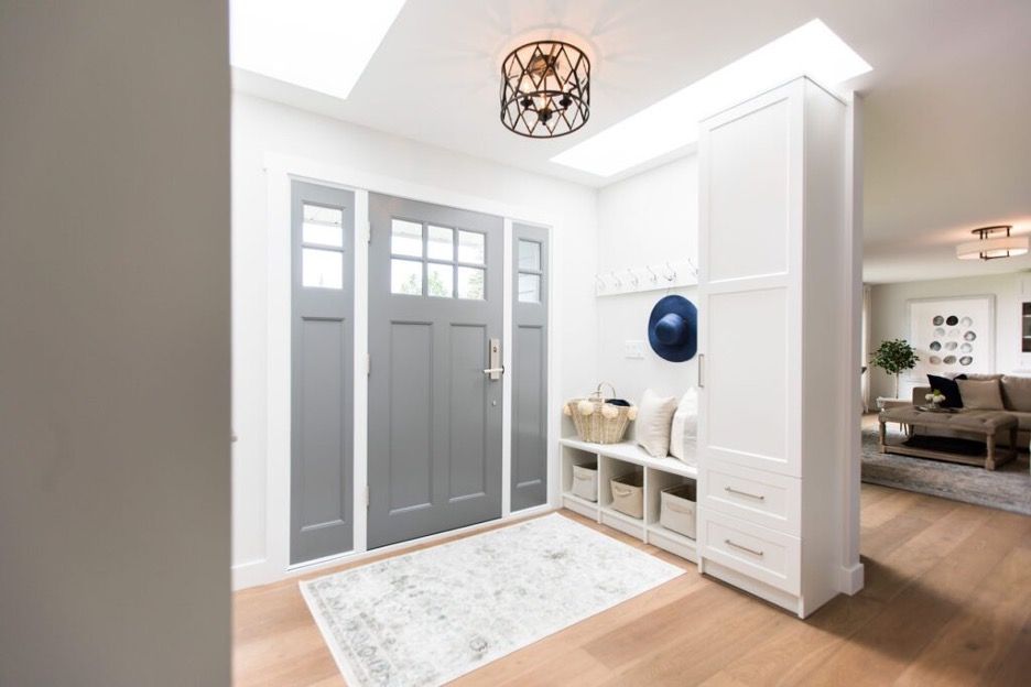Bright modern entryway with a gray front door, white built-in bench, and light wood floor