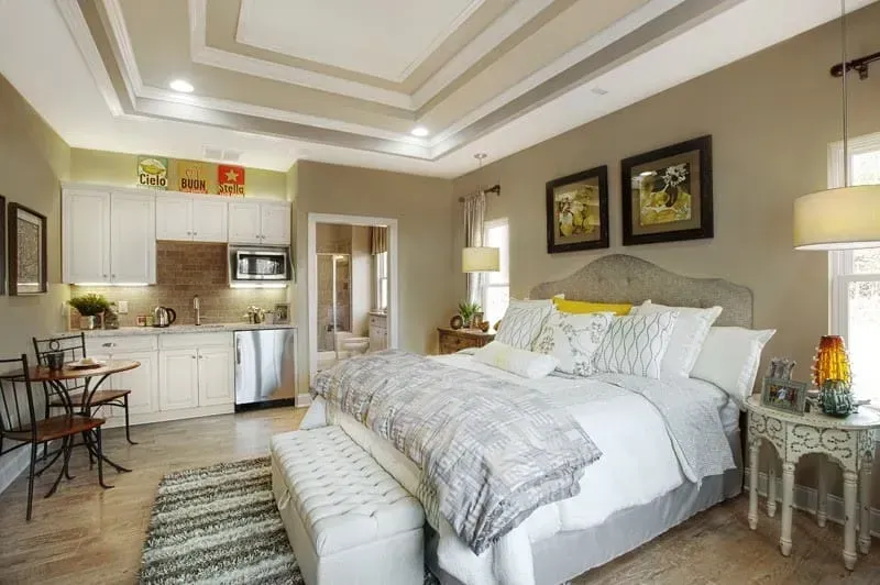 Cozy bedroom with king bed, kitchenette, beige decor, and two framed wall art pieces