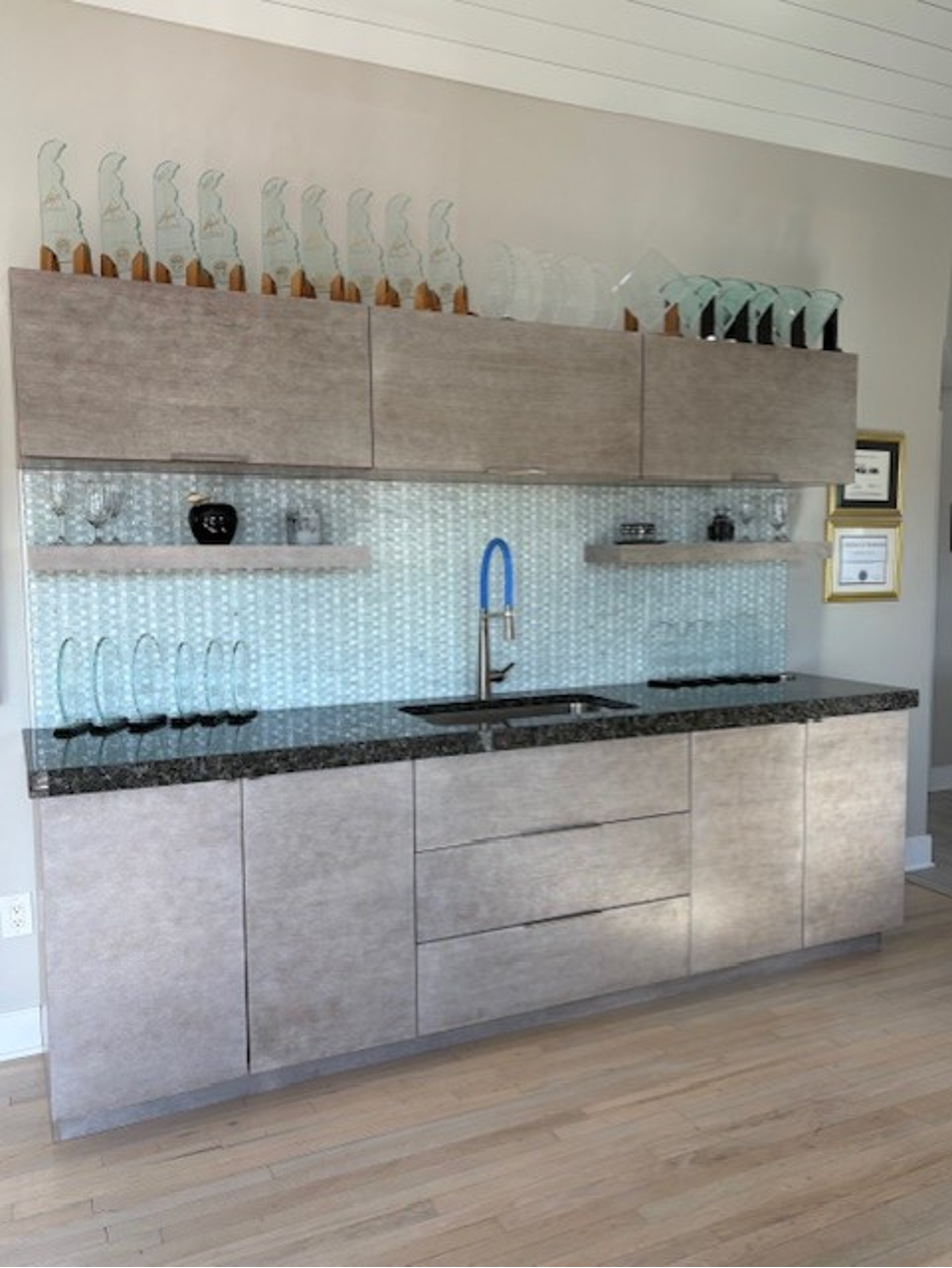 Modern kitchen wall with gray cabinets, black countertop, open shelves, and a blue faucet.