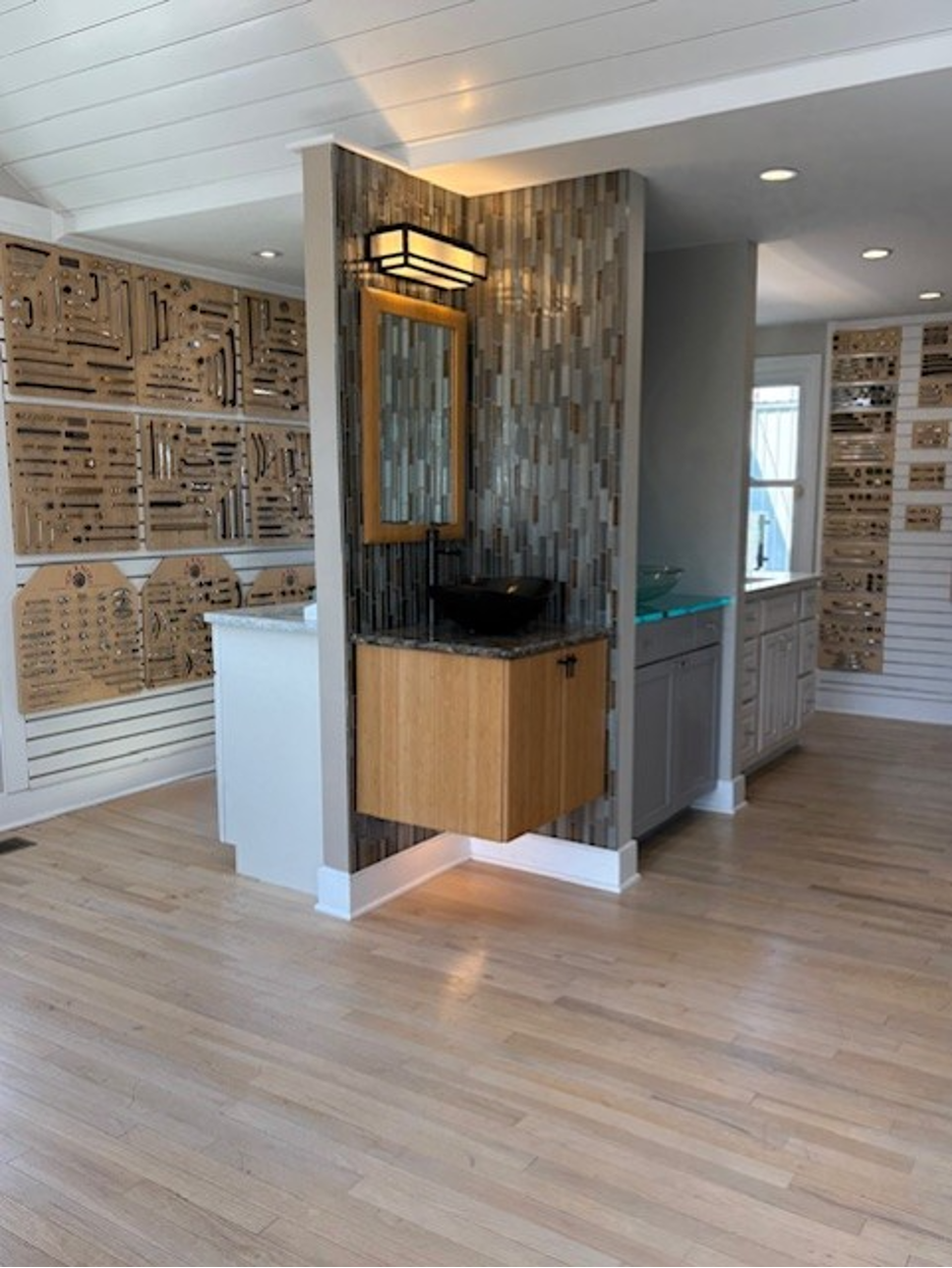 Modern lobby with a small wood vanity, black sink, mirror, and warm lighting on a light wood floor.