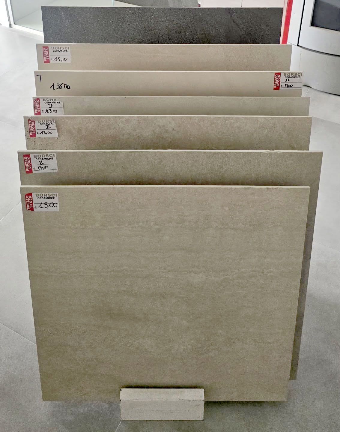 Pila di campioni di piastrelle quadrate beige esposti in uno showroom.