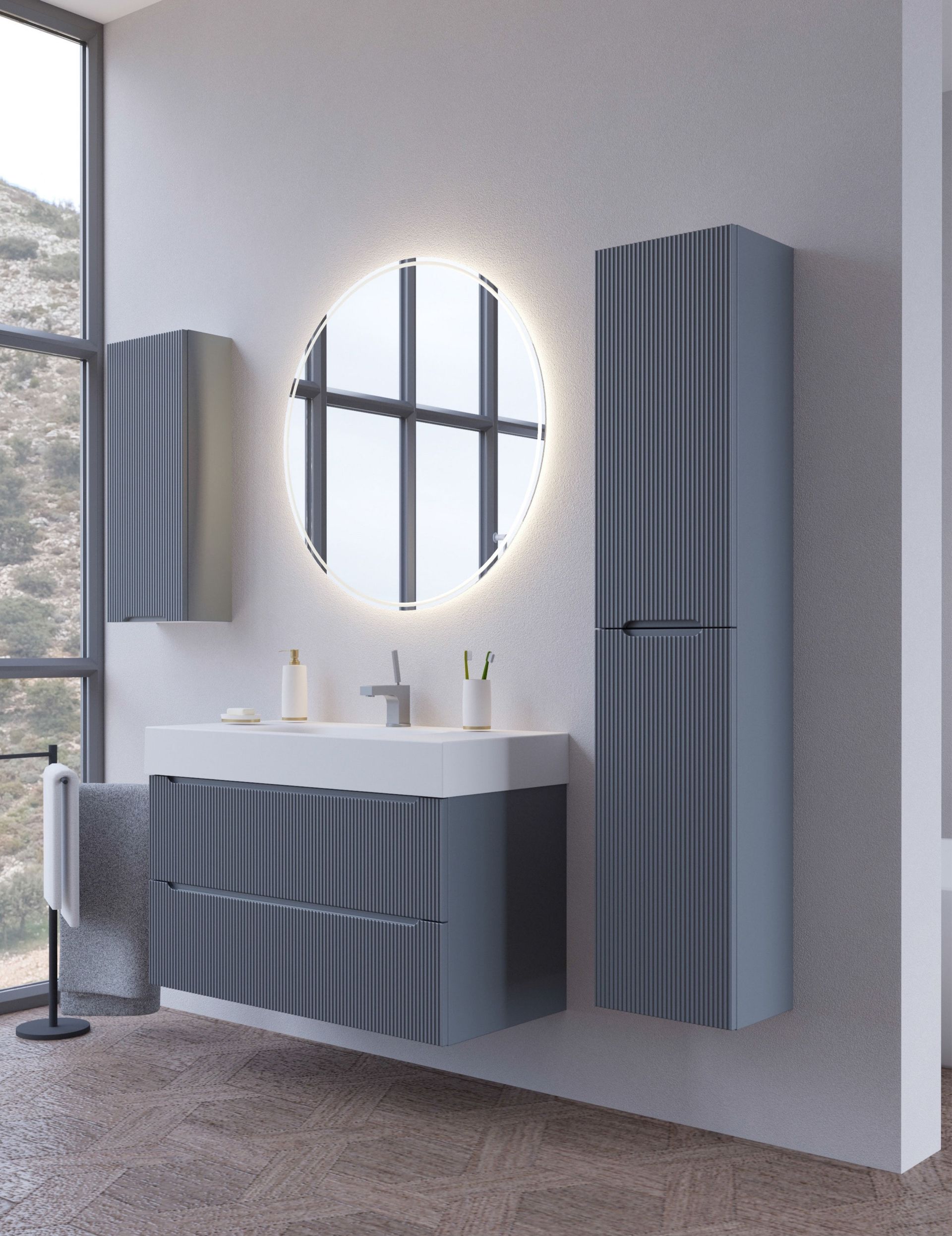 Bagno moderno di colore grigio con mobile lavabo sospeso, specchio rotondo e pensili alti accanto a una finestra.