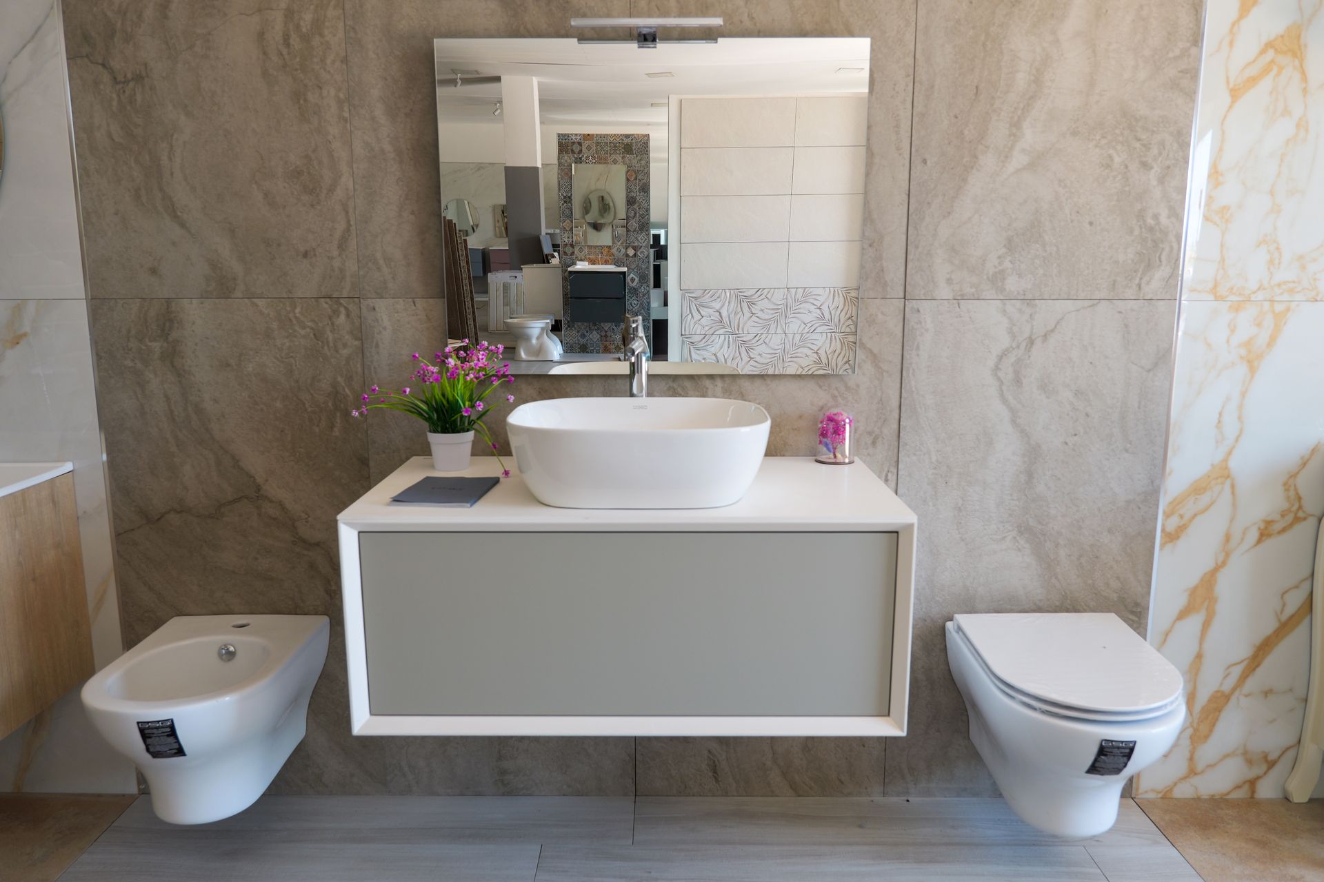 Mobile bagno moderno con lavabo a ciotola, specchio e due bidet a parete su entrambi i lati.