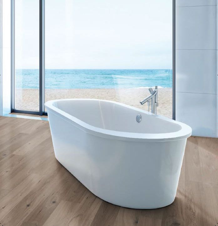 Vasca da bagno moderna e bianca in un bagno luminoso con vetrata a tutta altezza che offre una vista sull'oceano.
