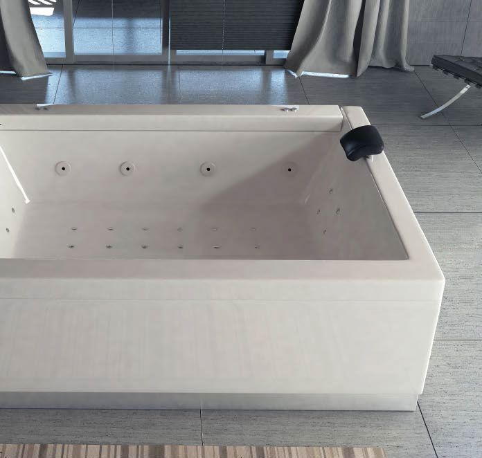 Vasca idromassaggio rettangolare bianca con maniglie nere, collocata in un moderno ambiente interno con vetrate a tutta altezza.
