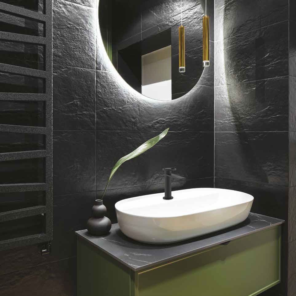 Mobile bagno moderno nero con specchio rotondo, lavabo bianco e una piccola pianta.