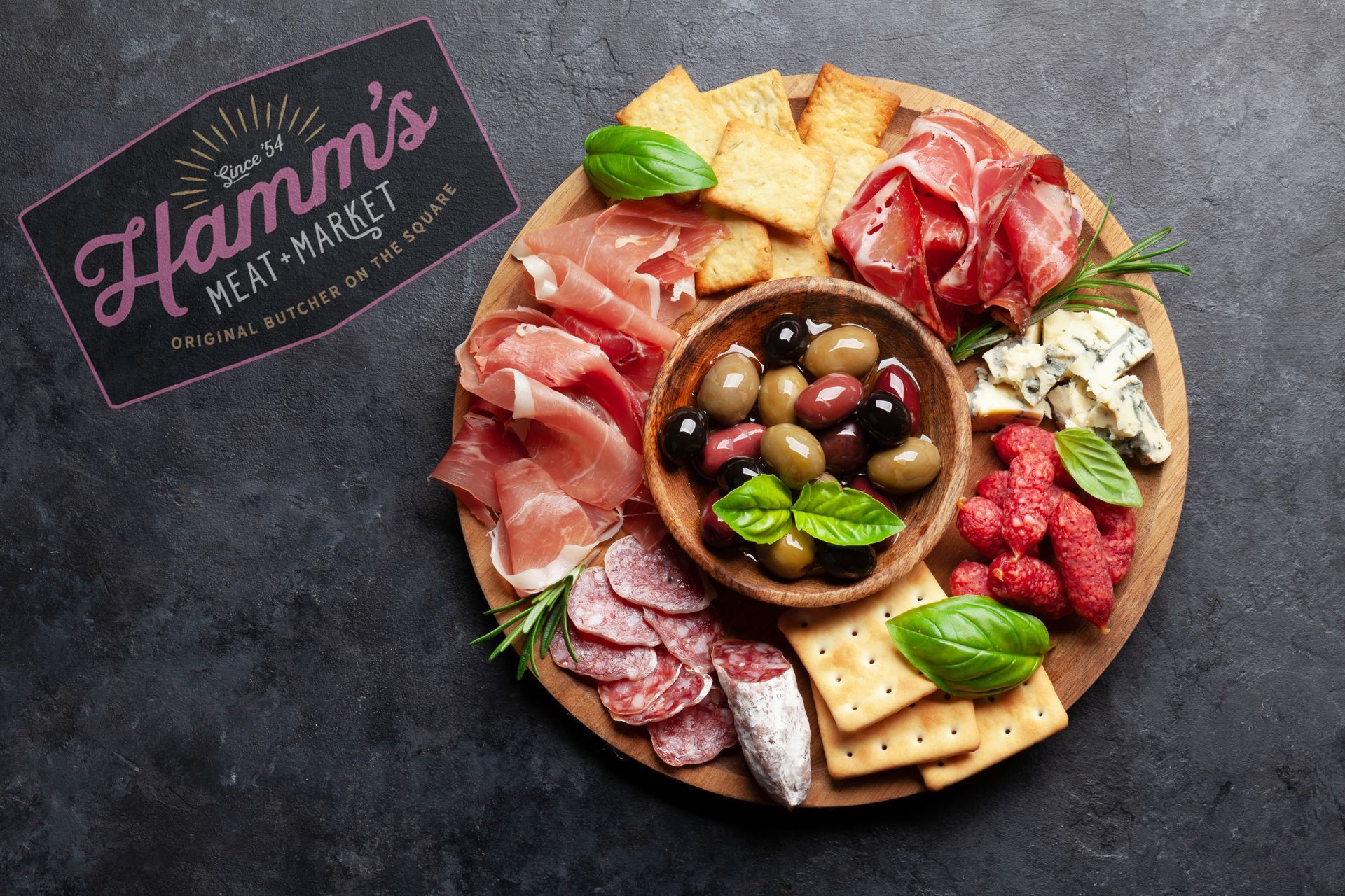 A wooden cutting board filled with a variety of meats and cheeses.
