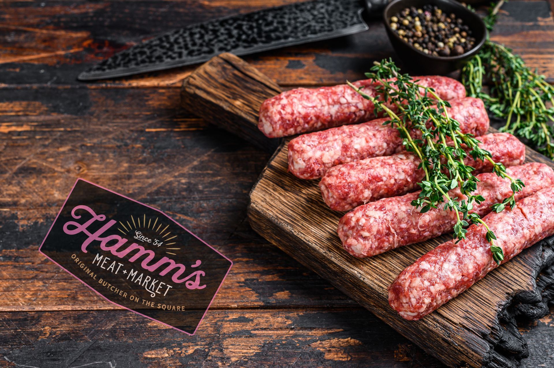 Raw sausages on a wooden cutting board with thyme.