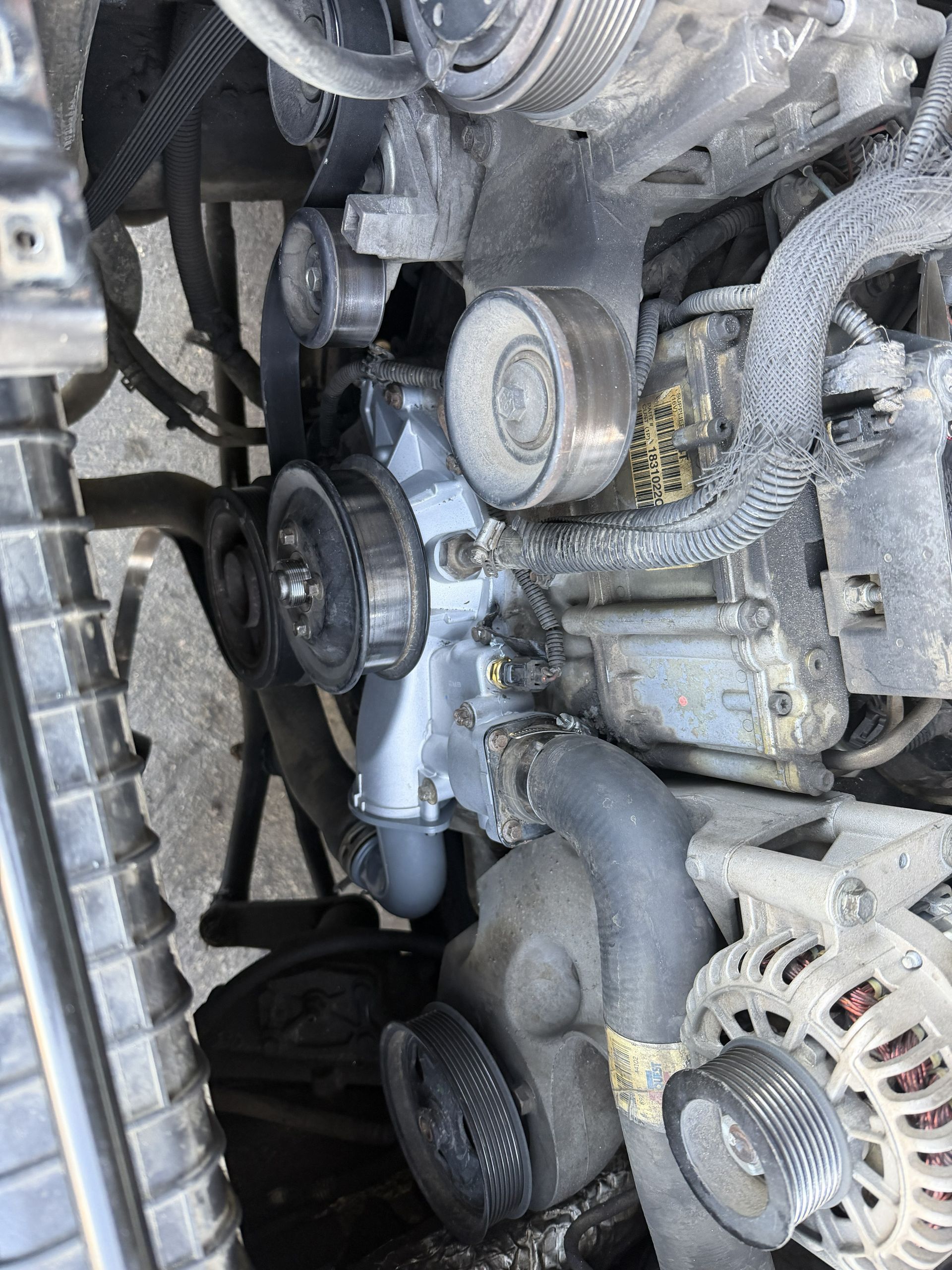 Close-up of a car engine with belts, pulleys, and hoses