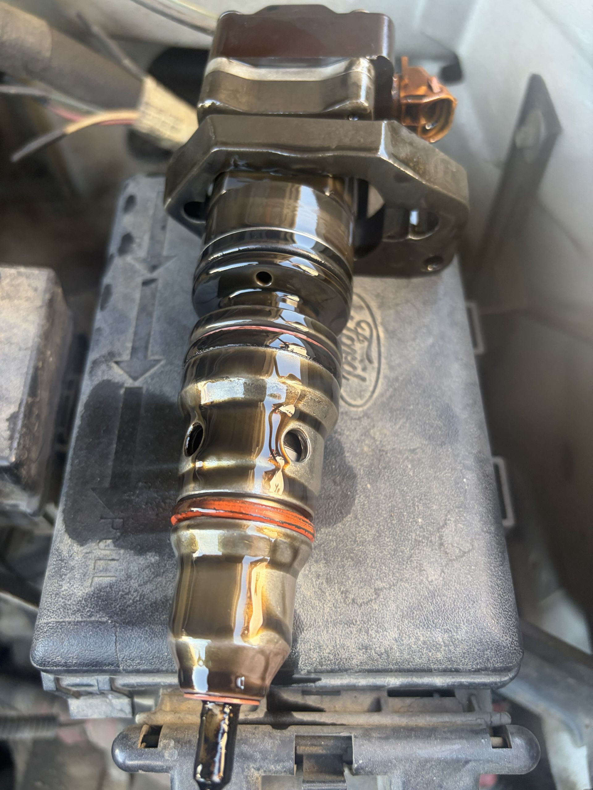Close-up of a metal shaft assembly clamped in a vise, with a copper ring and drilled holes visible.