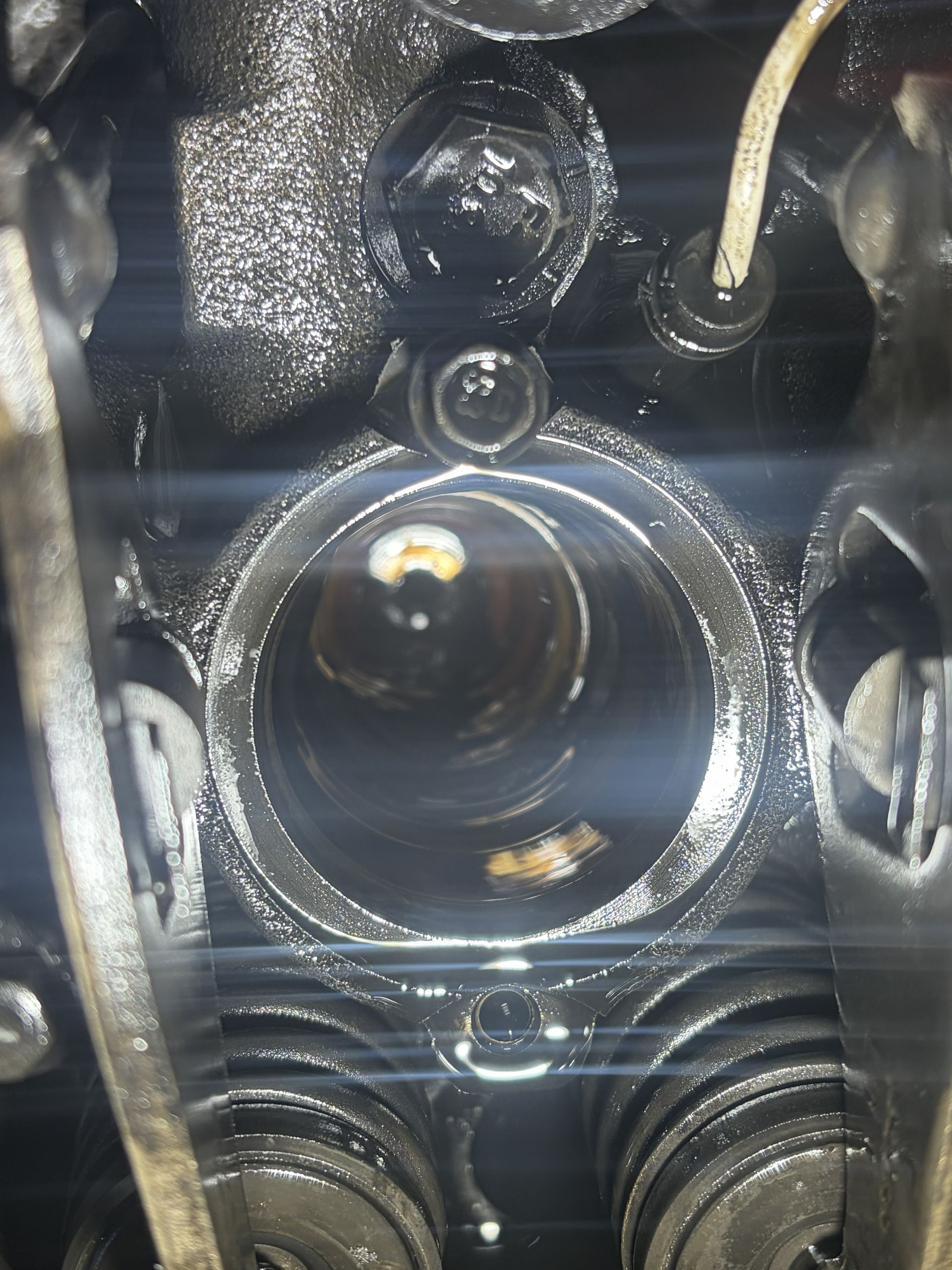 Close-up of a black camera lens inside a device, with wires and reflective metal parts around it.