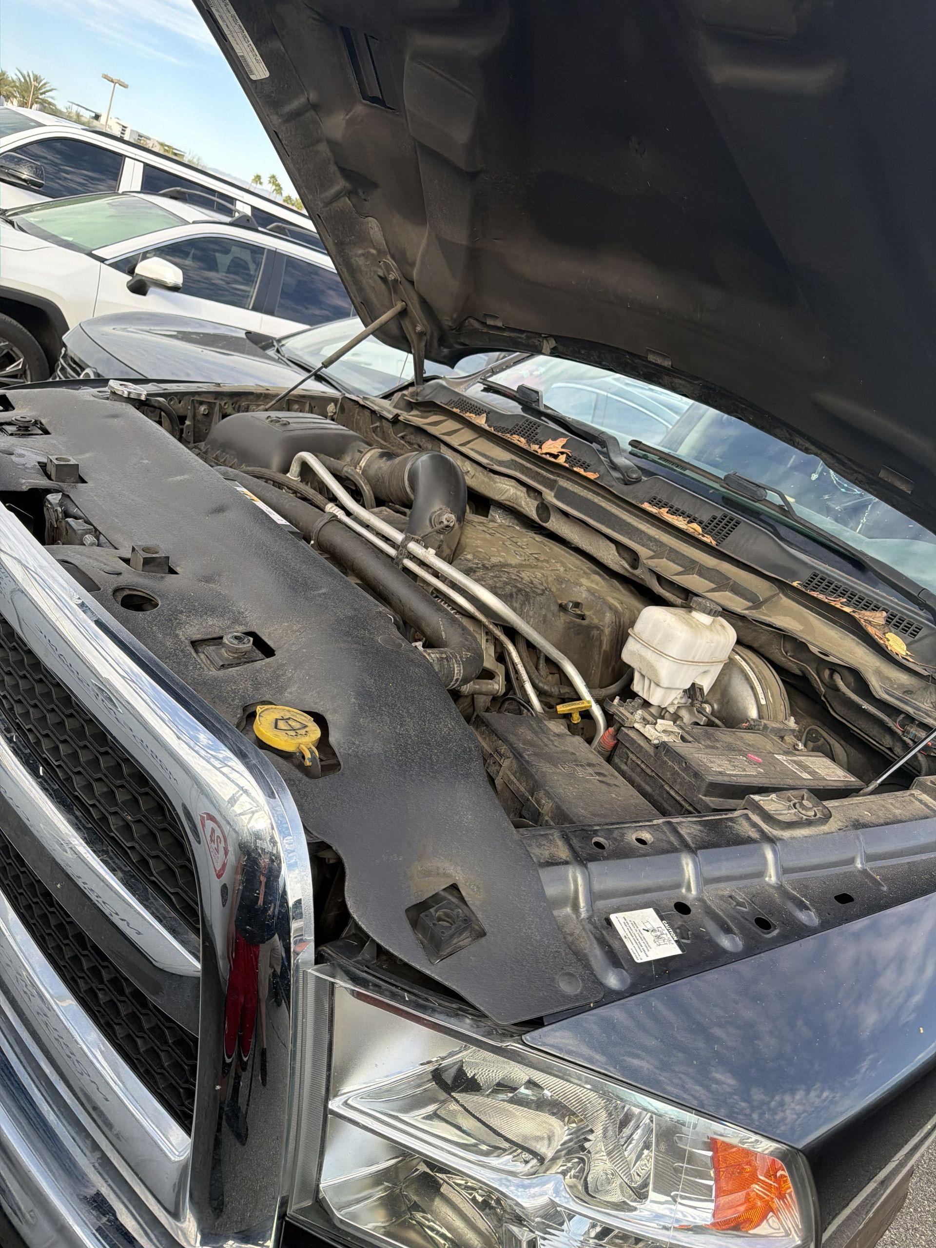 Pickup truck with hood open, showing engine bay and front grille in a parking lot.