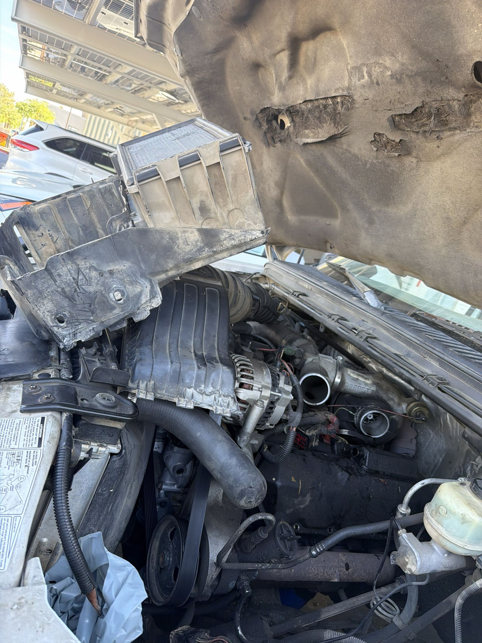 Burned car engine bay with melted parts and smoke damage under the open hood