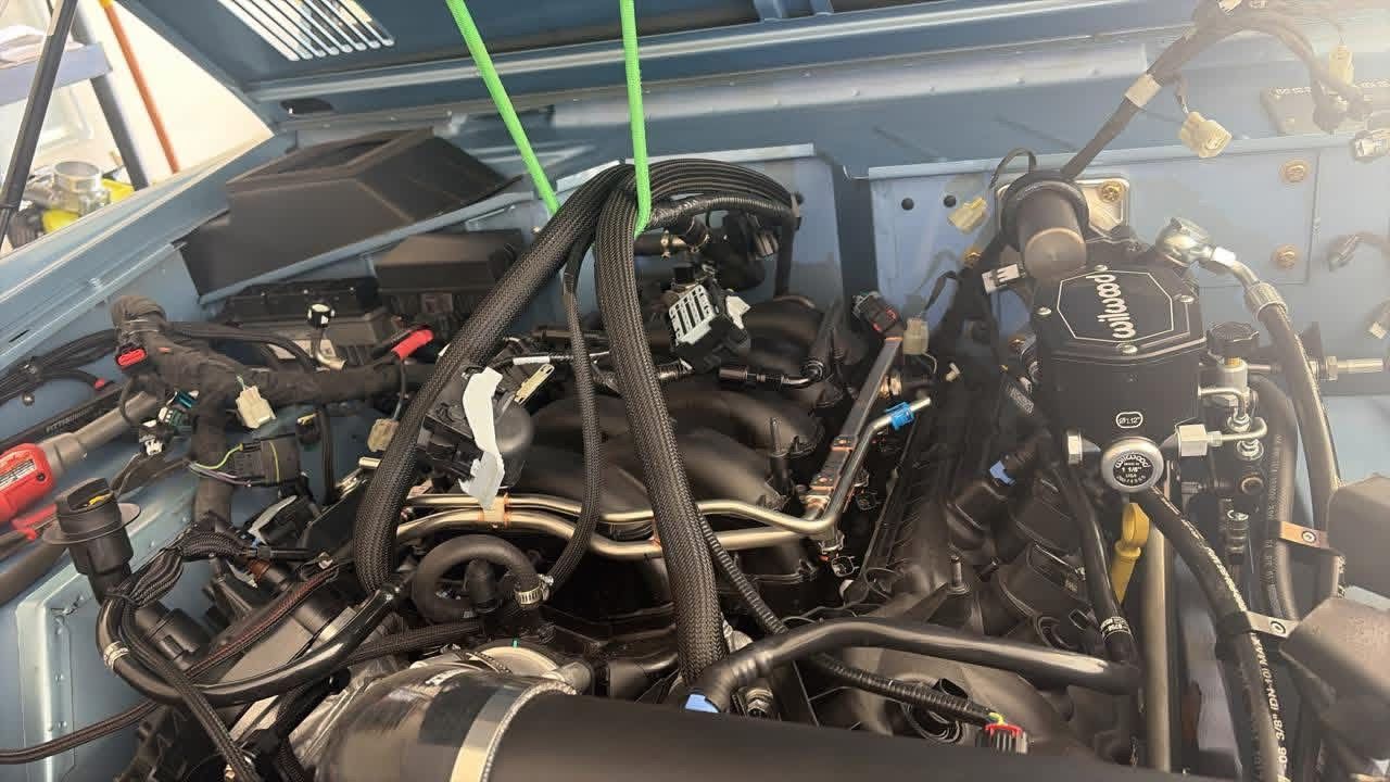 Close-up of a tangled engine bay with hoses and wiring inside a vehicle compartment