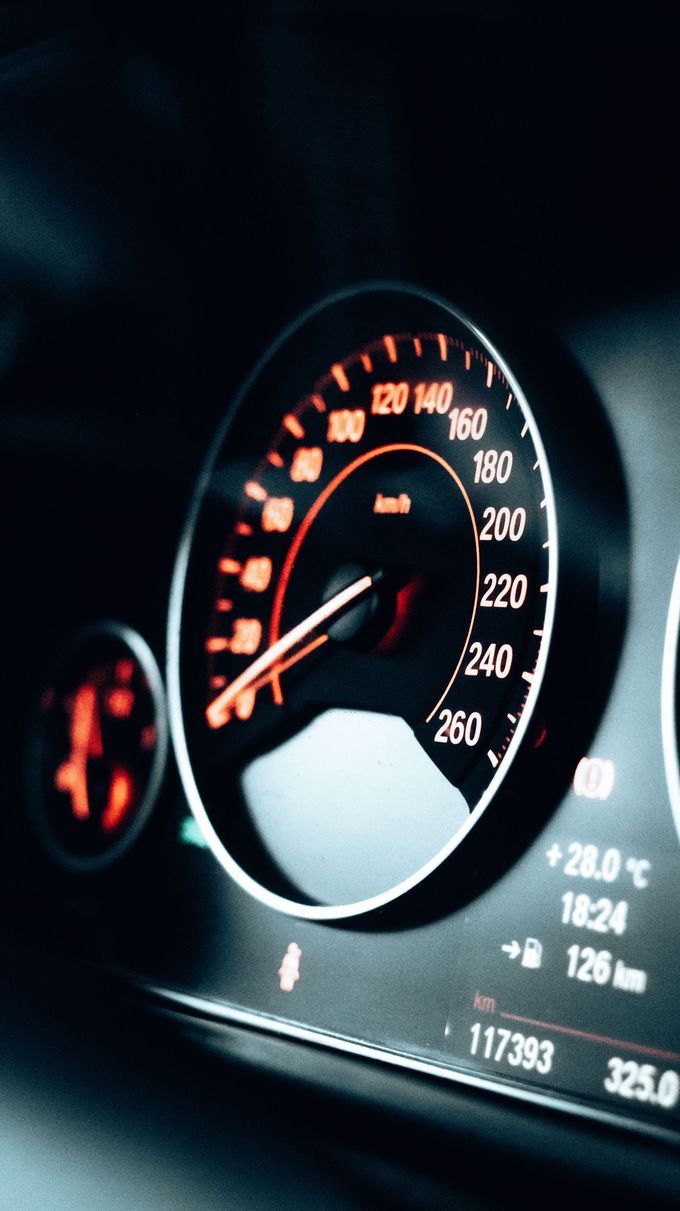 Close-up of a car dashboard speedometer with orange-lit gauges and digital display.