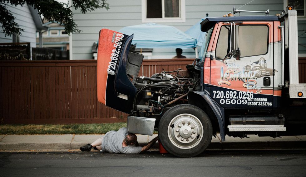 Tow truck loading a car after a roadside crash, with debris and a person lying on the street.