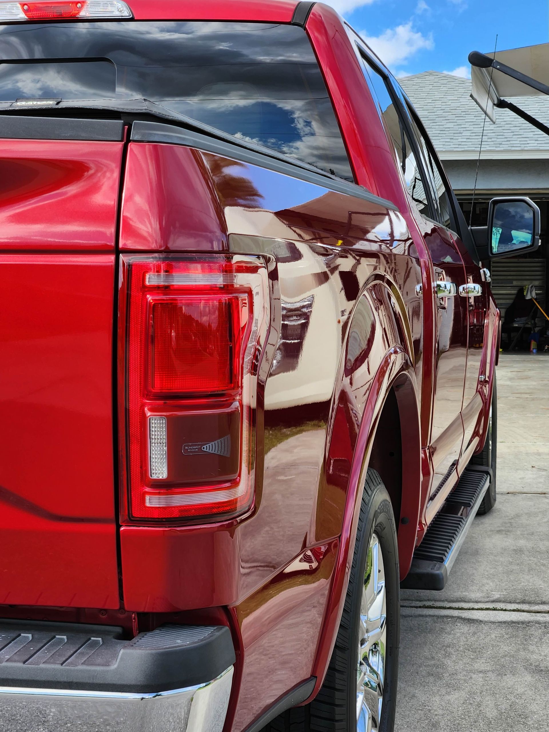 Red Ford pickup truck rear side view, shiny paint.