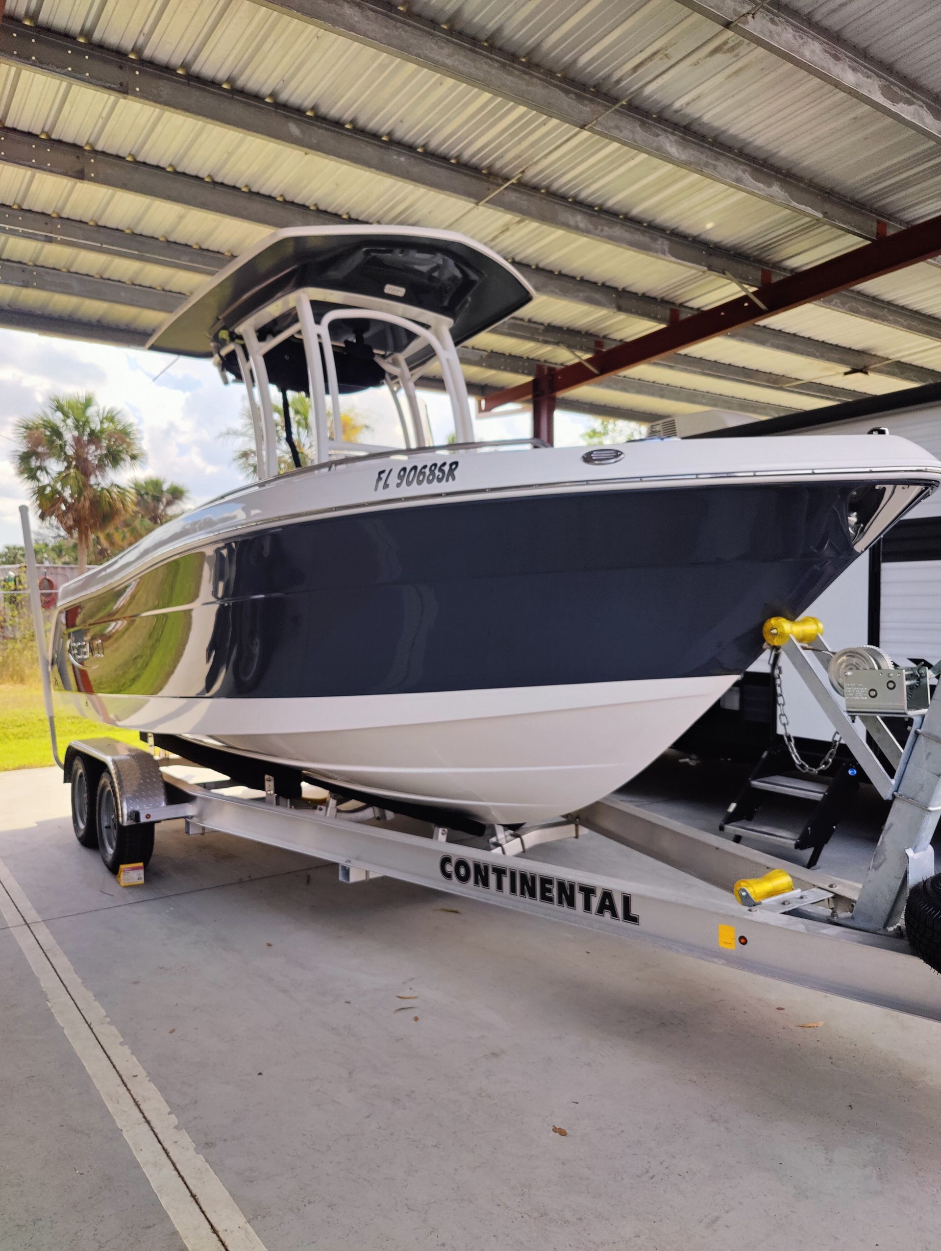 Boat on a trailer, navy and white, under a metal roof,