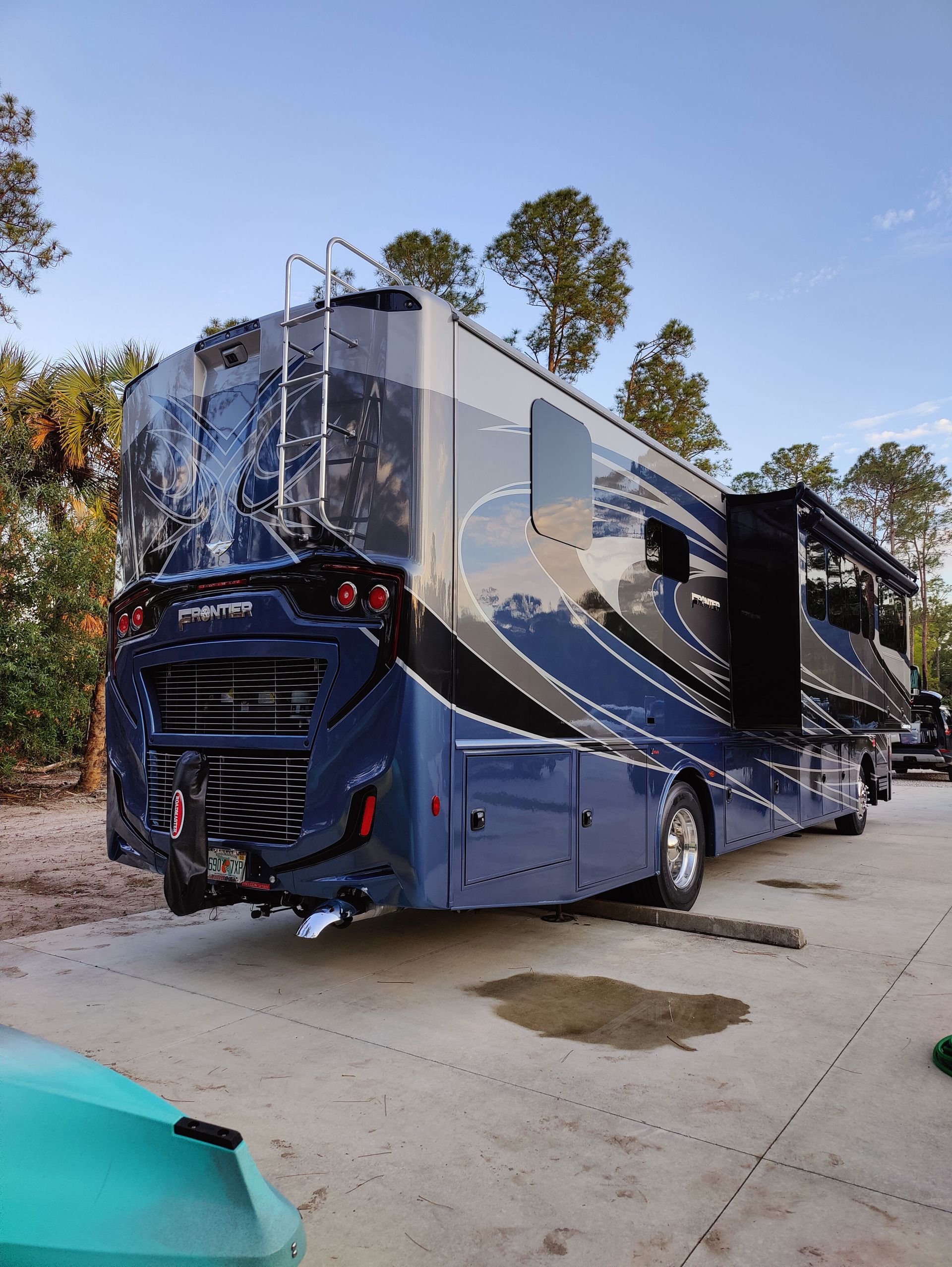 Large blue and black RV parked outdoors, with the slide-out extended.
