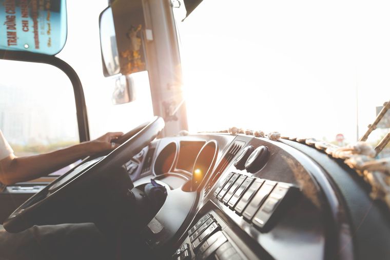 A man is driving a truck with the sun shining through the window.