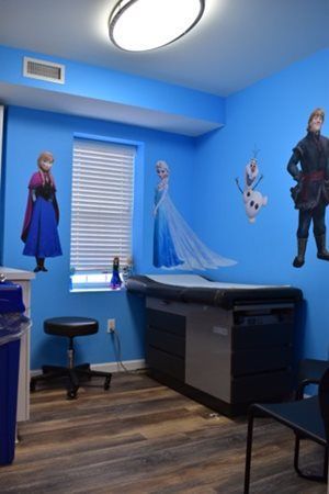 Blue room with Frozen character wall decals, a window, desk, and wood flooring