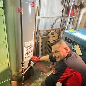 Man working on a water heater in a utility room, smiling.