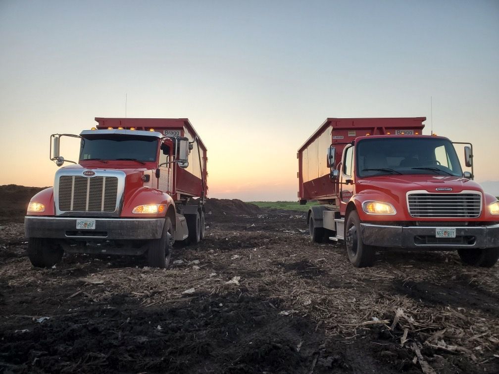 Two Dumpster Trucks on a Landfill — Melbourne, FL — Braggs Roll-Off Dumpsters Inc.