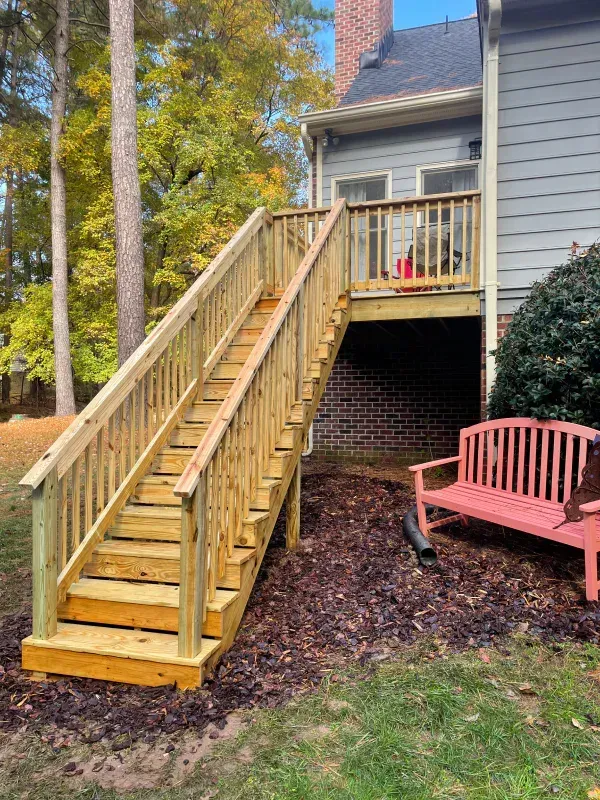 wood deck with tall staircase up to it. Red wood bench off to the site