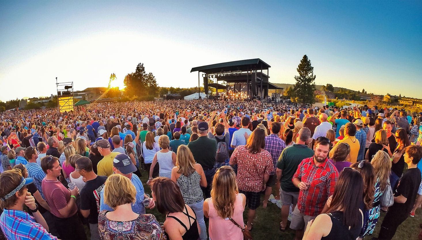 A large crowd of people are standing in front of a stage at a concert.