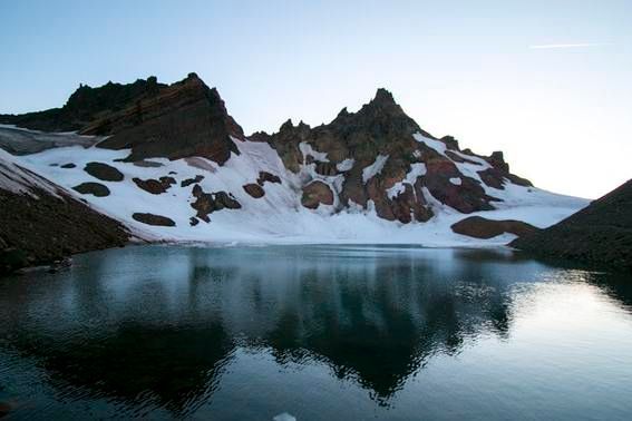 A mountain with snow on it and a lake in front of it