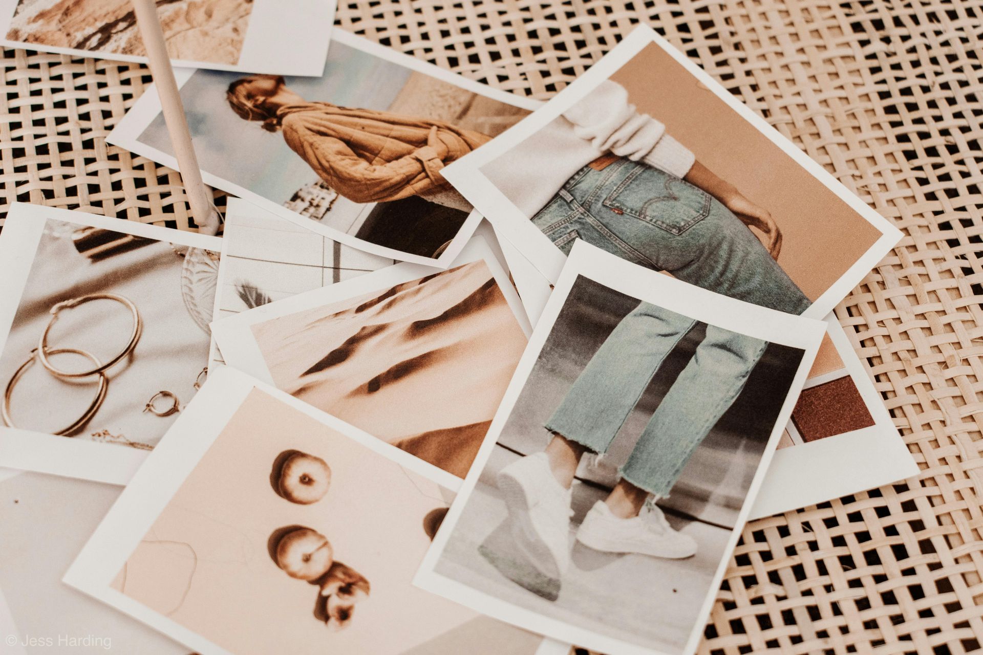 A person is holding a piece of paper over a pile of pictures on a table.