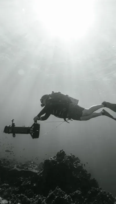 Scuba diver swimming above a coral reef in hazy underwater light