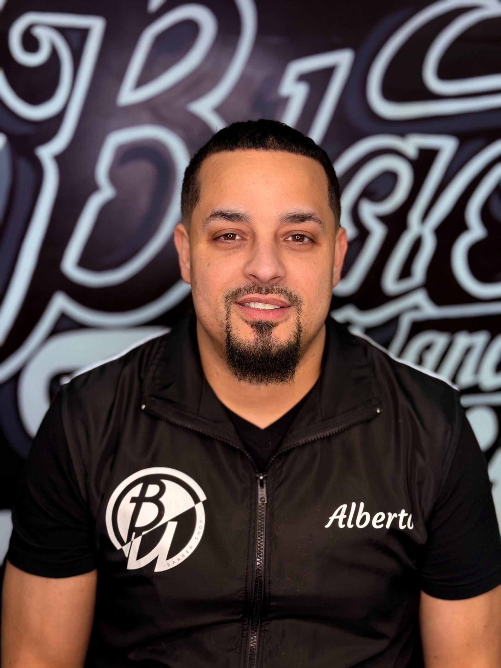 Man with goatee in black vest, BW logo, and Alberto name. Gray and black background with text.