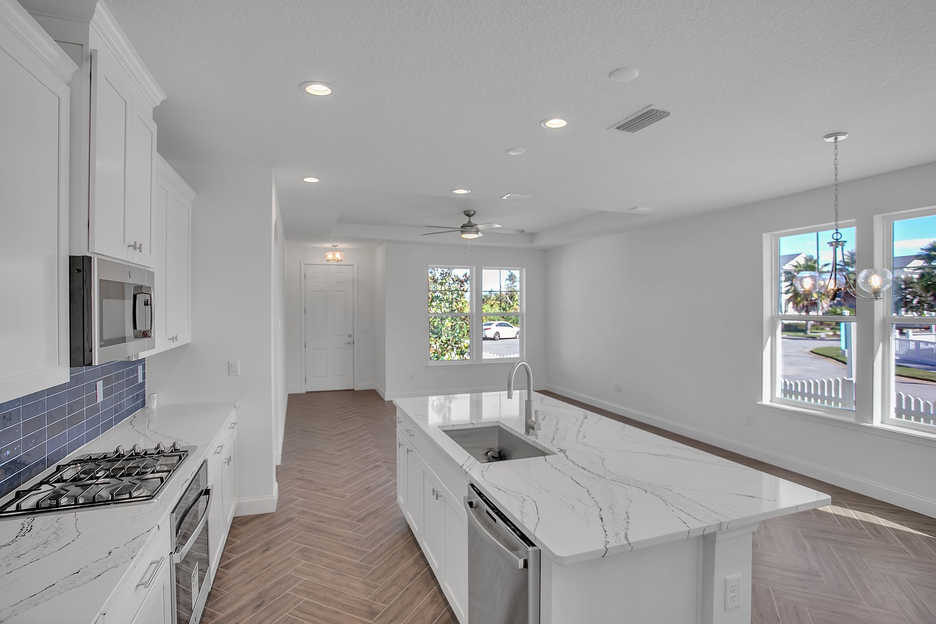 An empty kitchen with white cabinets , stainless steel appliances , and a large island.