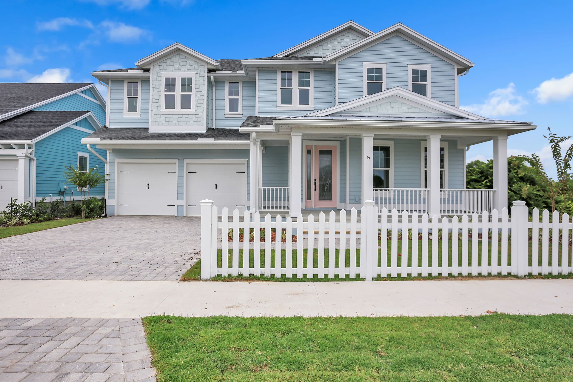 A large blue house with a white picket fence in front of it.