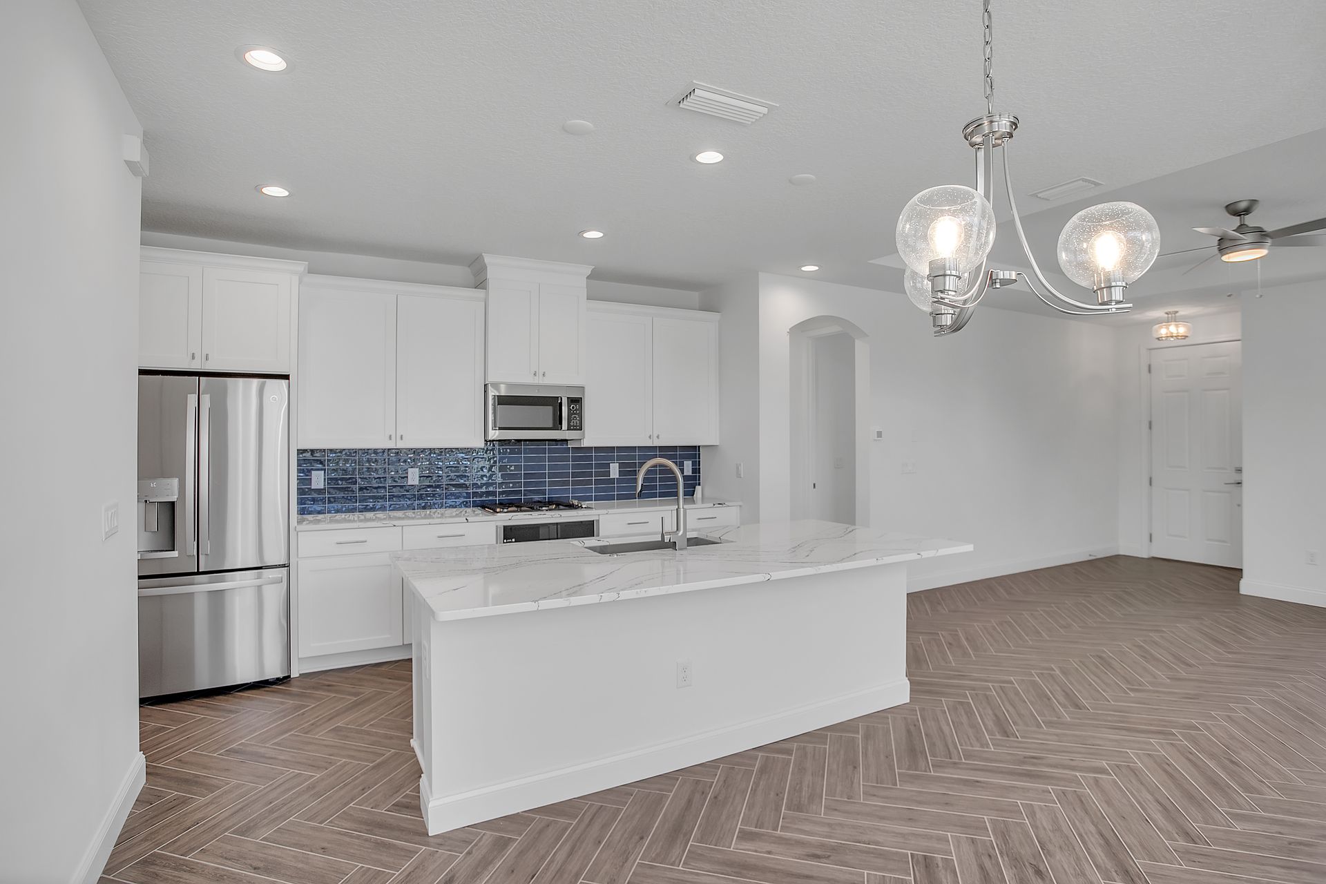 A kitchen with white cabinets , stainless steel appliances , and a large island.