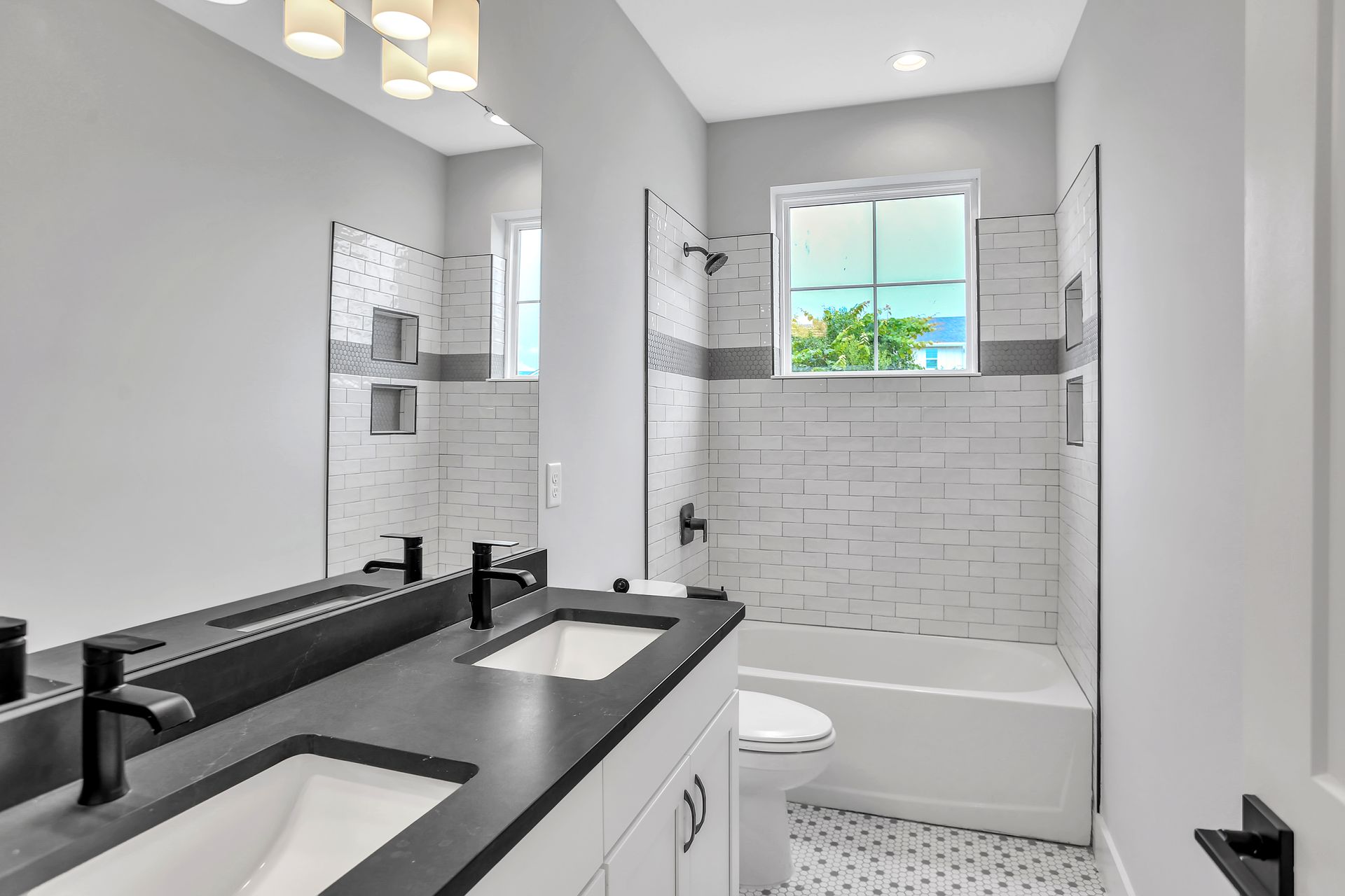A bathroom with two sinks , a toilet , and a window.
