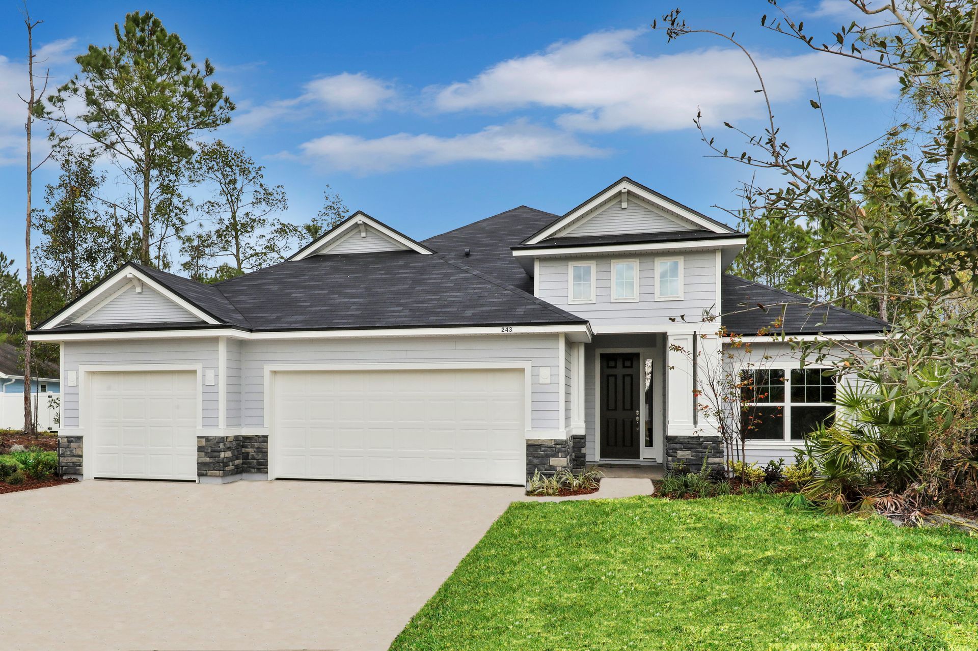A white house with a black roof and two garage doors