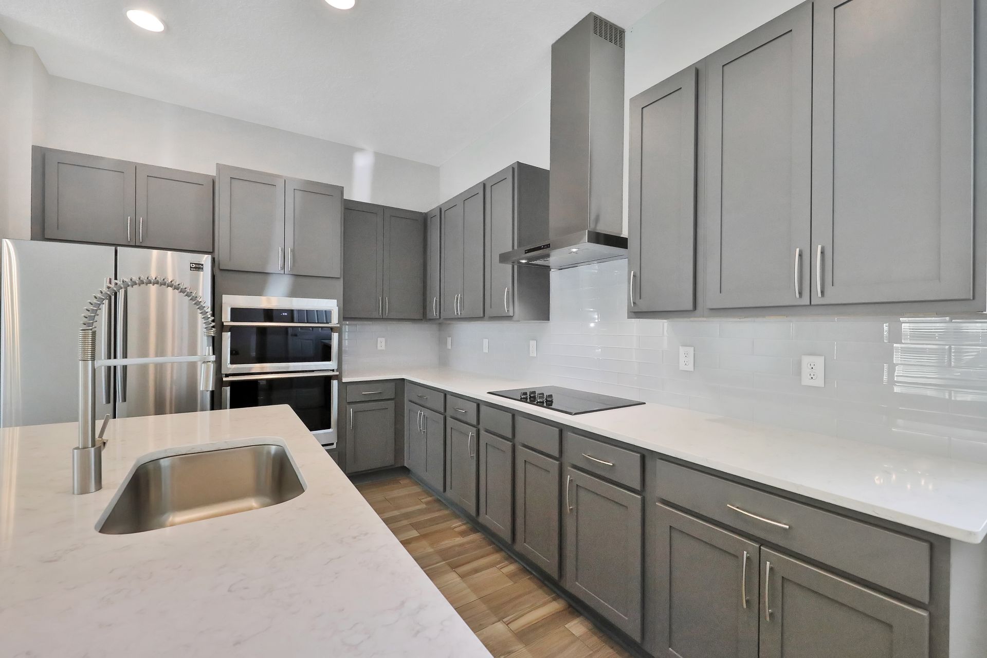 A kitchen with gray cabinets and white counter tops