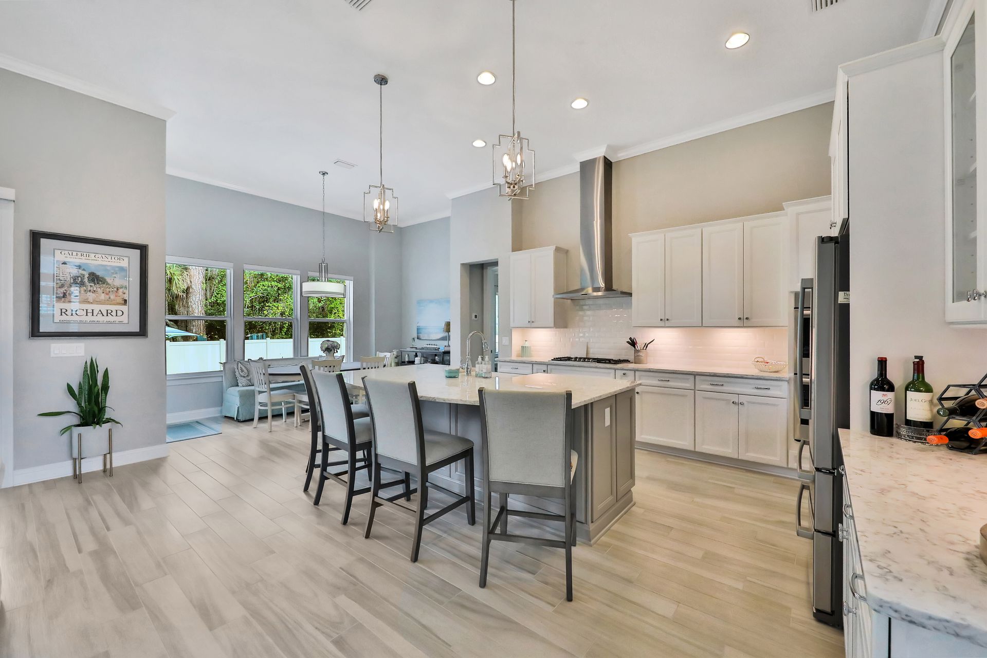 A kitchen with a large island and stools and a refrigerator.