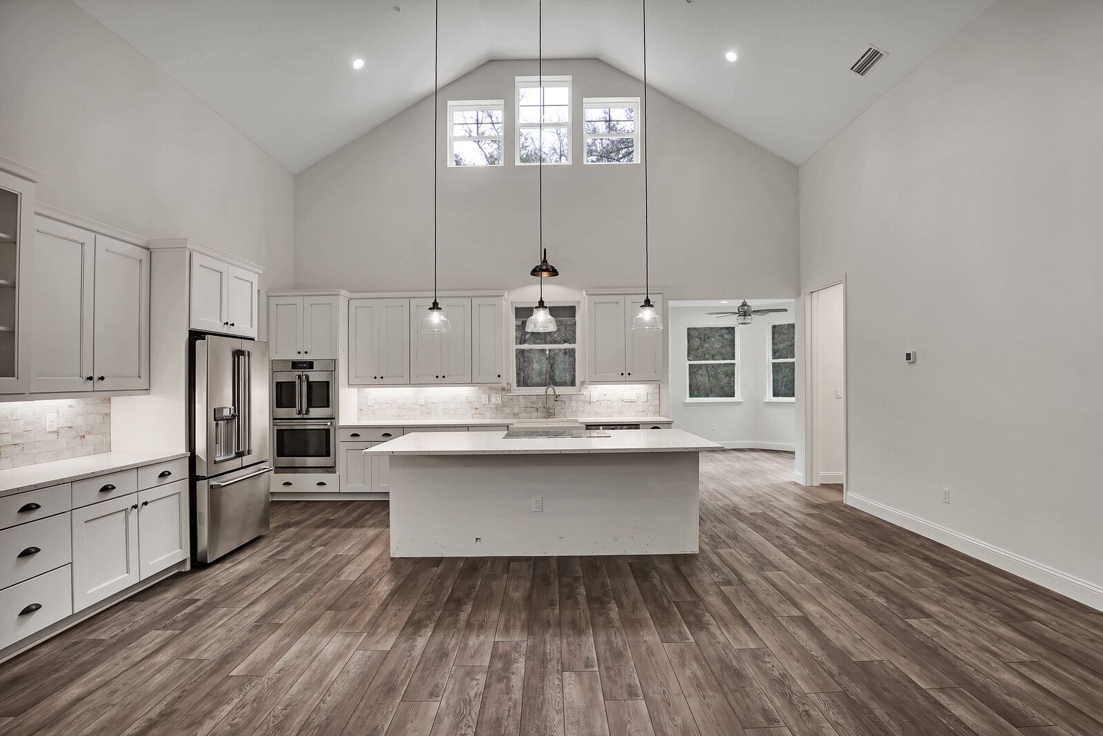 A kitchen with white cabinets , stainless steel appliances , and a large island.